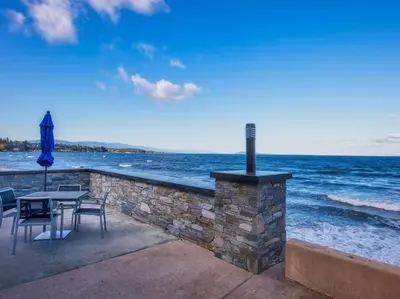 a patio with a table and chairs next to the ocean at Qualicum Beach Ocean Suites in Qualicum Beach