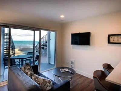 a living room with a couch and a flat screen tv at Qualicum Beach Ocean Suites in Qualicum Beach