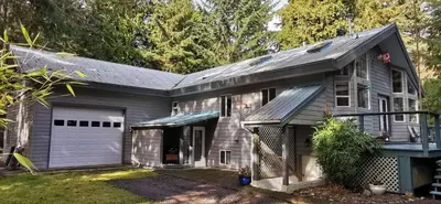 a gray house with a garage at Gabriola Island B&B By The Sea in Gabriola