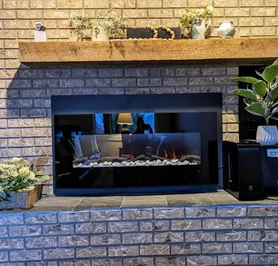 a brick fireplace with a fire in it at By the Sea in Campbell River