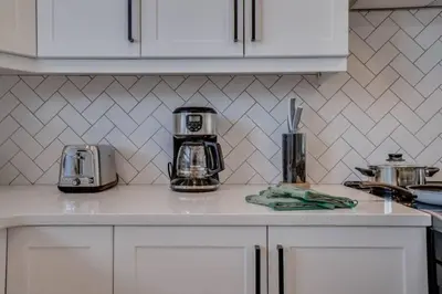 a kitchen with white cabinets and a counter top at LovelyHome-Foosball-NearAirport-5 Queen Beds -Air conditioning in Edmonton
