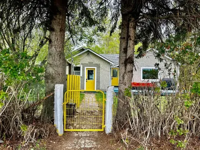 a yellow gate in front of a house with trees at Farmstay in Edmonton in Duffield