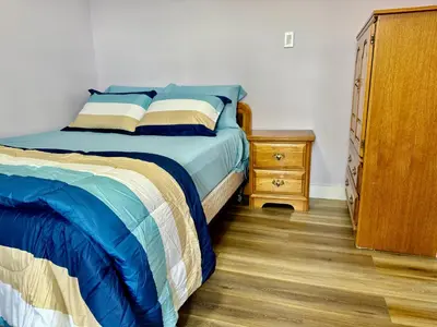 a bedroom with a bed and a wooden dresser at Farmstay in Edmonton in Duffield