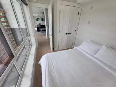 a bedroom with a white bed and a hallway at Premium Deluxe PeachView Suites 3BR in Peachland