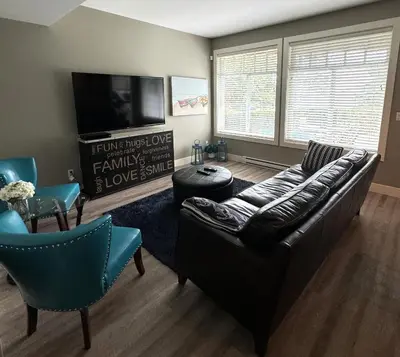 a living room with a leather couch and a tv at White Rock Beach getaway in White Rock