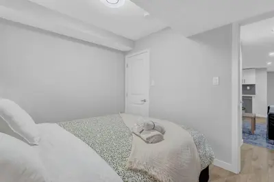 a white bedroom with a bed with a towel on it at ModernSuite*NearAirport*2Queens*2Bedroom*FullKitchen in Edmonton