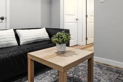 a living room with a black couch and a wooden coffee table at ModernSuite*NearAirport*2Queens*2Bedroom*FullKitchen in Edmonton