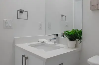 a white bathroom with a sink and a potted plant at Townhome with Free Parking, Near Downtown in Calgary