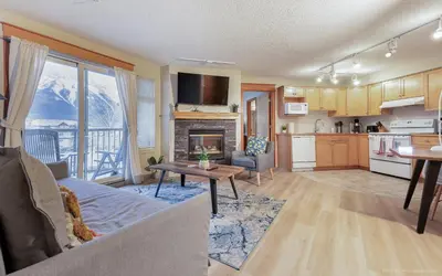 a kitchen and living room with a couch and a table at Lovely Mountain View 2 Bedroom Suite in Canmore
