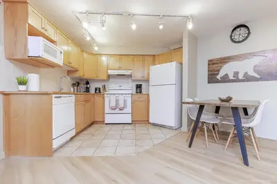 a kitchen with a table and a white refrigerator at Lovely Mountain View 2 Bedroom Suite in Canmore