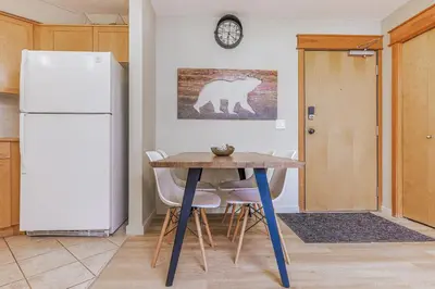 a kitchen with a table and a white refrigerator at Lovely Mountain View 2 Bedroom Suite in Canmore