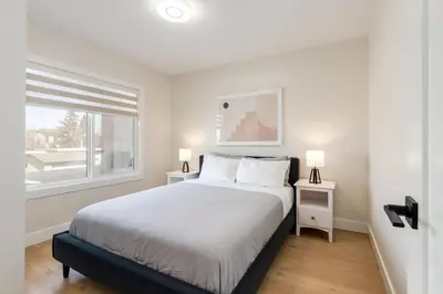 a white bedroom with a bed and a window at Pet Friendly & Accessible, 4 Beds in Calgary