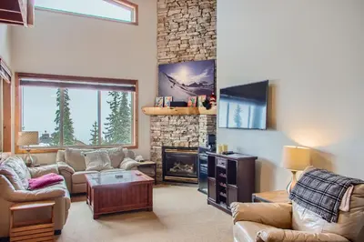 a living room with couches and a stone fireplace at Snowy Creek by Okanagan Premier in Big White
