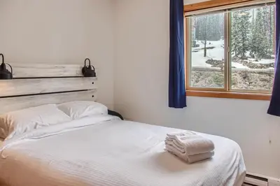 a bed with two towels on it in a room with a window at Snowy Creek by Okanagan Premier in Big White