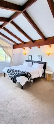 a bedroom with two beds and a ceiling with beams at White House Tofino Downtown Villa in Tofino