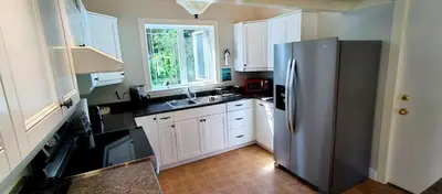 a kitchen with a stainless steel refrigerator and white cabinets at White House Tofino Downtown Villa in Tofino
