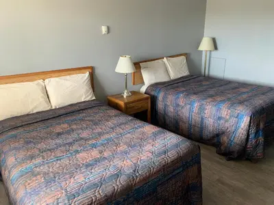 a hotel room with two beds and two lamps at Wild Rose Inn in Vegreville