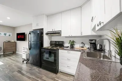 a kitchen with white cabinets and a black refrigerator at Modern & Unique Studio Unit in Edmonton