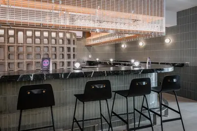 a bar with four black stools in a kitchen at Gravity Haus Revelstoke in Revelstoke