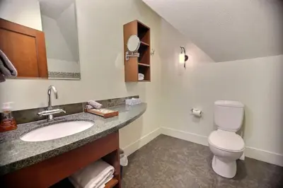 a bathroom with a sink and a toilet and a mirror at Magnificent Mountain Penthouse - Hot Tub & Pool managed by Little Sister Getaways in Canmore