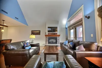 a living room with leather couches and a fireplace at Magnificent Mountain Penthouse - Hot Tub & Pool managed by Little Sister Getaways in Canmore