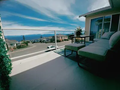 a balcony with a couch and a table and a street at Ocean View Home Nanaimo in Nanaimo