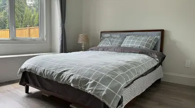 a bed in a white room with a window at Home In Vancouver in Richmond