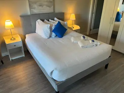 a bedroom with a bed with blue and white pillows at Gibsons Landing Inn in Gibsons