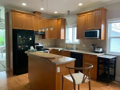 a kitchen with wooden cabinets and a black refrigerator at 3 Bedrooms 1 Bath in SHARE HOUSE at Coquitlam Central Mall & skytrain in Port Coquitlam