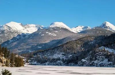 a snow covered mountain range with a lake in the foreground at 2BR in Blackcomb Greens, Wood Fireplace, Hot Tub Access, Mountain Views, Free Ski Shuttle, Parking in Whistler