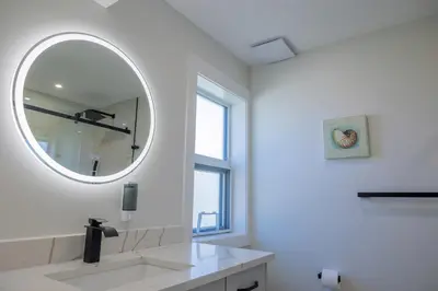 a white bathroom with a mirror and a sink at Premium Deluxe suites 201 in Peachland