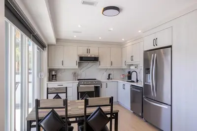 a kitchen with white cabinets and a table and chairs at Premium Deluxe suites 201 in Peachland