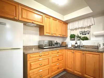 a kitchen with wooden cabinets and a white refrigerator at 2BR 1BA Garden View Guest Suite - King-size Bed - Free Parking in Vancouver