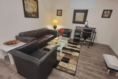 a living room with a leather couch and a piano at Brand New Suite in the Lakes in Calgary