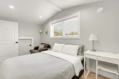 a white bedroom with a bed and a window at New laneway house near Airport, World Cup stadium, Downtown, UBC in Vancouver