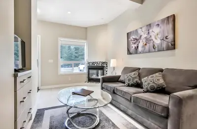 a living room with a couch and a glass table at Mountain Surrounded Lodge in Harvie Height in Canmore