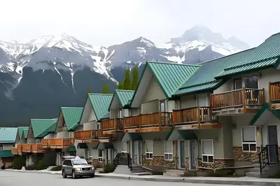 a car parked in front of a row of buildings with mountains at Mountain Surrounded Lodge in Harvie Height in Canmore