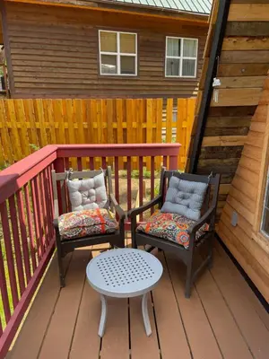 two chairs and a table on a deck at Bratty Catty Cabin in Powell River