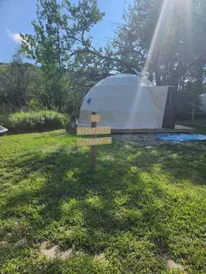 a sign in the grass with a tent in the background at D3 Rainforest Getaway Dome- 2Dbl beds in Drumheller