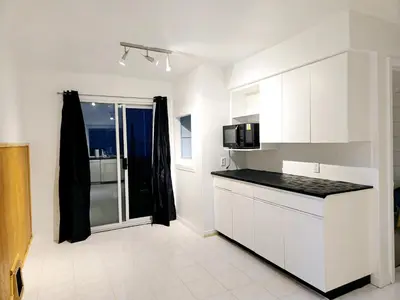 a kitchen with white cabinets and a black counter top at Lovely Cozy Room! with Attached Private Bath in the Heart of Vancouver! Private Parking & Self Check-in! in Vancouver