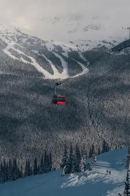 a red ski lift flying over a snow covered mountain at Mid Century Modern - Studio w Pool & Hot Tub in Whistler