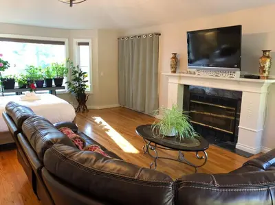 a living room with a couch and a fireplace at Heated pool, hot tub, 4 AC lake view bedrooms in West Kelowna