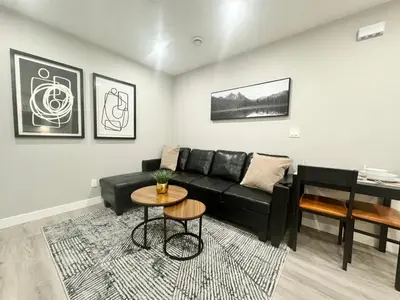 a living room with a black couch and a piano at Private Modern Retreat in the NW - 12 mins to Airport - Near Shops - Easy Banff Access in Calgary