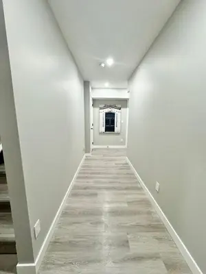 an empty hallway with white walls and a window at Private Modern Retreat in the NW - 12 mins to Airport - Near Shops - Easy Banff Access in Calgary