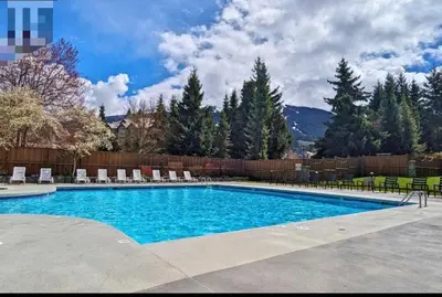 a swimming pool with chairs and a fence at a fully renovated condo near village centre with MT view and close to lift in Cascade lodge in Whistler