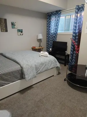 a bedroom with a bed and a chair and a window at Genesis Townhouse in Calgary