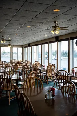 a dining room with tables and chairs and windows at Talbot Arm Motel in Destruction Bay