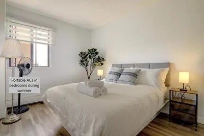 a bedroom with a large white bed with a window at Stylish DT Views at Stampede w Free Parking and AC in Calgary
