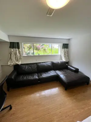 a black leather couch in a living room with a window at Green House in Vancouver West in Vancouver
