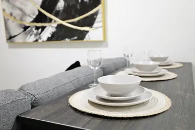 a table with plates and bowls and wine glasses at Elegant Escape with King Bed, Long Stays, WEM, Disney in Edmonton